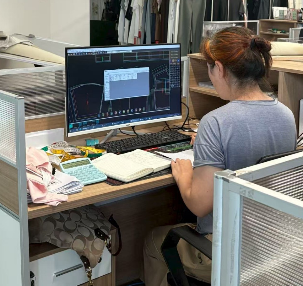 Technician developing a garment pattern on CAD software at a design workstation