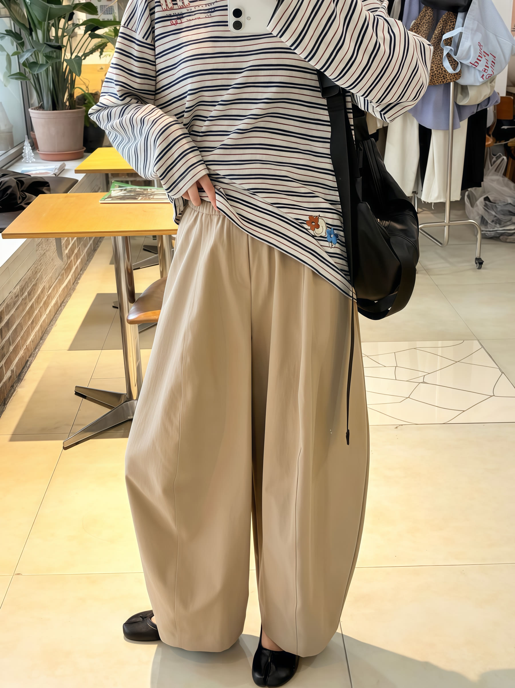 Striped top styled with beige wide-leg trousers in a mirror try-on