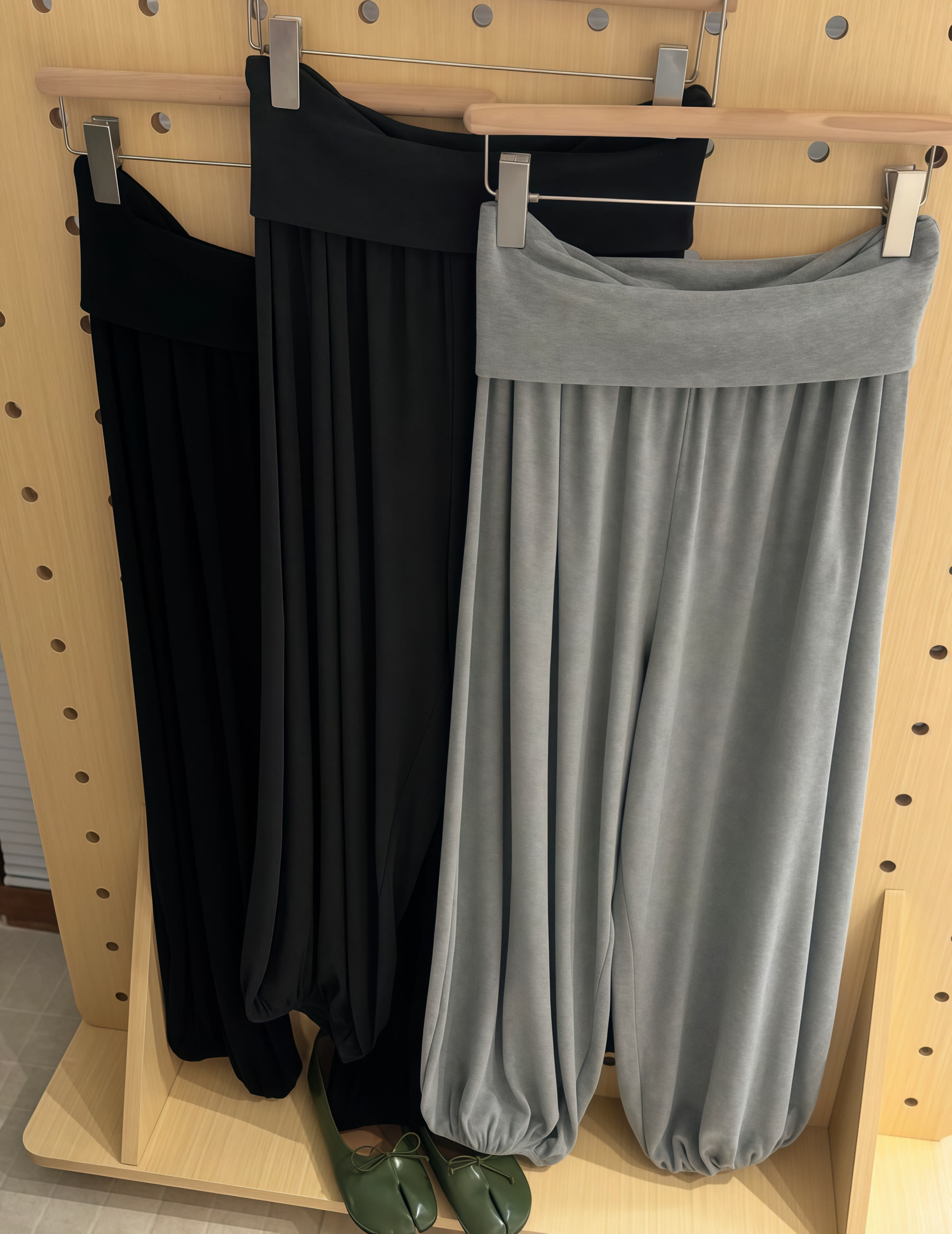 Black and grey wide-leg trousers and skirts displayed on a wooden rack